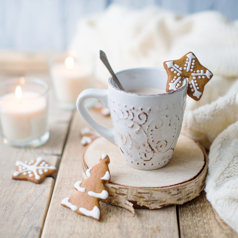 Cup of hot chocolate with gingerbread and candle.